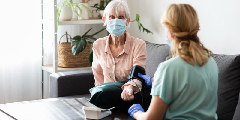 elder-woman-with-medical-mask-having-her-blood-pressure-checked-nursing-home